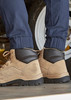 A pair of cuffed navy work pants worn with tan and black boots, set against a vehicle backdrop.
