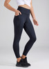 A pair of navy women's 7/8 length leggings with pockets, complete with a logo, worn with a white top and black shoes.