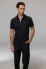 A black polo shirt with contrasting white accents, modelled by a man wearing black trousers. The shirt features a logo.