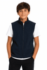 A boy stands wearing a navy blue vest over a white T-shirt, with his hands in his pockets. The vest has branding.