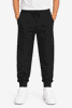 Tapered fleece kids pants in black with elastic waistband and side pockets, paired with white sneakers.