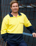 A man wearing a hi-vis two-tone yellow and navy cotton fleecy sweatshirt with a zip and pocket, posed against a metal backdrop.