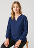 A navy long sleeve blouse with a V-neck and gathered sleeves, worn by a seated model.