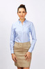A woman in a light blue button-up long sleeve shirt paired with a beige skirt, standing against a plain background.