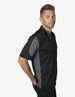 A polo shirt in black with grey side panels and a logo on the chest, modelled by a man.