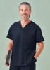 A unisex navy pulse V-neck scrub top with a pocket, modelled by a smiling man holding a clipboard.