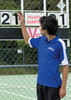 A young person adjusts a scoreboard while wearing a blue and white polo shirt with a logo.