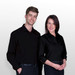 A black button-up shirt designed for women, featuring a sleek, fitted look and long sleeves. It has branding.