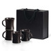 A set of four espresso mugs in dark brown stacked inside a black gift box with handles.