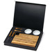 A gourmet cheese set in a black box featuring a wooden board, knives, and two small white bowls.
