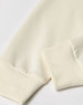 A crew neck sweater in a creamy off-white colour, featuring ribbed cuffs and a smooth fabric texture.