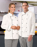 A unisex executive chef jacket in white with black trim, worn by a woman and a man in a kitchen setting.
