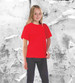 A red junior tee displayed on a child against a textured grey background, featuring a logo.