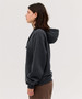 A grey hoodie with a hood, featuring a relaxed fit and long sleeves. The model is shown from the side.