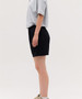 Black sports shorts displayed on a model wearing a grey shirt, featuring an elastic waistband and a simple design.