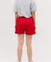 Red sports shorts are displayed, featuring an elastic waistband and a simple design, paired with a grey top.