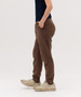 Brown track pants featuring a logo, displayed on a model wearing a navy shirt and beige shoes.