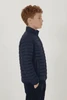 A side view of a young boy wearing a navy blue puffer jacket with a high collar and a logo on the chest.