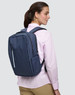 A navy blue backpack with a sleek design is worn on the back of a person, featuring zippers and compartments.