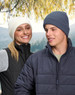 A white and a navy blue cable knit snug beanie displayed on models in outdoor attire, set against a nature backdrop.
