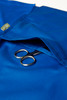 A blue women's scrub top with a pocket containing a pair of scissors and featuring a logo.