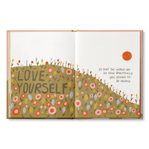 Inside of book open to page with the encouraging, uplifting statement: "Love yourself so that the world can see how beautifully you deserve to be treated." The page has an illustration of a hillside filled with flowers and a bright orange sun above.