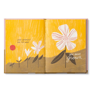 Inside of book open to page with the encouraging, uplifting statement: Love yourself for the ways you have grown." The page has a bright yellow background with an  illustration of a flower growing from a seedling to full bloom.
