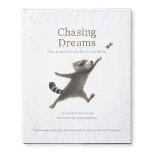This image shows the front cover of the gift book, Chasing Dreams: How to add more daring to your doing, written by Kobi Yamada. The cover has an illustration by Charles Santoso of an adorable raccoon reaching for a butterfly fluttering into the sky. 