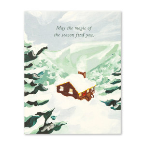This holiday card front features an illustration of a cabin in the mountians covered with snow, and reads "May the magic of the season find you." The card was illustrated by Margaret Jeane Smith.