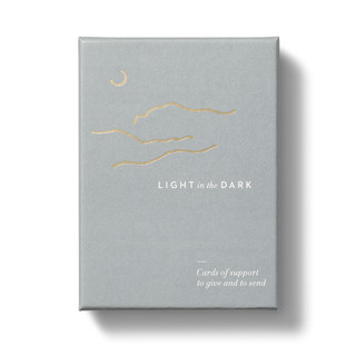 The front cover of the stationary box set, with the title "Light in the Dark" written in the center of the box, and a gray background. 