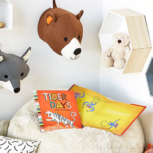 Lifestyle photo of the children's illustrated book "Tiger Days" written by M.H. Clark and illustrated by Anna Hurley. The book is open to a page that features silly, playful monkeys and reads "On monkey days I'm silly and I'm ready for some fun. I want to laugh and swing and play and be around my friends all day."