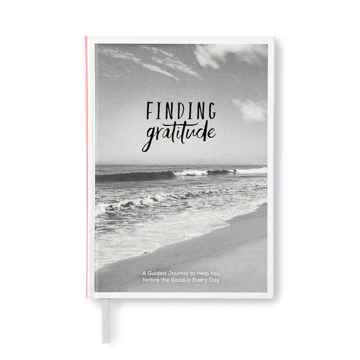 The front cover of the prompted journal, "Finding Gratitude: A guided journal to help you notice the good in every day" has a black and white photo of the ocean shore with pinks accents on the spine.