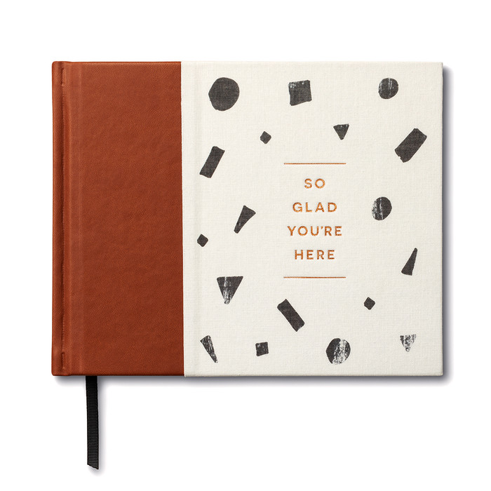 The front cover of this all-occasion guest book has leather brown, white and black design with the title "So Glad You're Here" written across the center. The title copy is gold foiled and debossed.