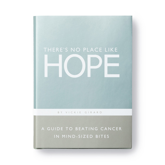 The front cover of this encouragement gift book has a light blue background with the title "There's No Place Like Hope" written across the front. The lower section of the book has a gray background with a short description of the book, "A guide to beating cancer in mind-sized bites".