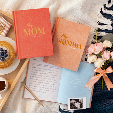 Lifestyle photo of interview keepsake heirloom books, "My Mom: In Her Own Words" and "My Grandma: In Her Own Words". The book is opened to a page with a prompt that reads "Life Lessons: What have been some of the hardest challenges for you in life? How have they affected you? What did you learn or gain from them?" A quote is beautifully designed on the opposite page that reads "Learning is ever young, even in old age."