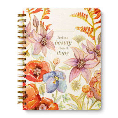 This image shows the front cover of a spiral notebook. The journal design is filled with beautiful garden flowers in orange, golden, purple, and blue hues, the background color is cream. The statement on the cover reads: "Seek out beauty where it lives."
