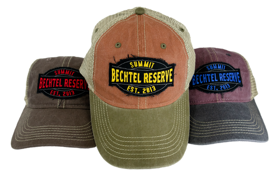 Weathered look Trucker Cap with front patch that says, Summit Bechtel Reserve, Established 2013 and has a plastic snap closure. Pictured left to right are Coffee/Khaki, Rust/Khaki, Henna/Khaki.