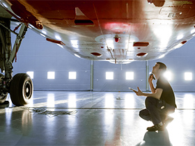 aviation mechanic looking at underside of aircraft