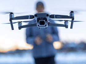 Drone with remote pilot in background