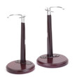 Two dark brown wooden doll display stands designed to fit 18-inch American Girl ® dolls are shown side-by-side against a solid white background. Each stand features a thick, circular wooden base, a wide vertical column, and a curved adjustable silver metal waist wire at the top to securely hold a doll.