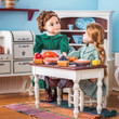 In an 18 inch doll kitchen setting there are two dolls at the 18" doll farmhouse style wooden table.