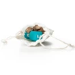 A small, white fabric drawstring pouch is shown open on a solid white background, revealing its contents. Tucked inside the bag are two miniature teal toy dreidels with Hebrew lettering alongside a cluster of small gold play coins. The pouch's white braided drawstrings spread out flat to either side on the reflective white surface.