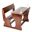 A miniature wooden pioneer school desk with an attached bench, showing  pens standing in the desktop slots.