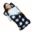 This studio product photograph shows an 18-inch doll tucked into a miniature plaid sleeping bag, isolated against a solid white background.