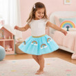 Blue mesh tutu has sparkly rainbow appliques and gold waistband on a little girl dancing in her bedroom