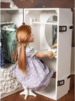In play scene, an 18 inch doll sits on the vanity stool admiring herself in the vanity mirror. A couple dresses of 18 inch doll clothing hangs on the rack next to her. In play scene, an 18 inch doll sits on the vanity stool admiring herself in the vanity mirror. A couple dresses of 18 inch doll clothing hangs on the rack next to her.