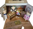 An open, miniature suitcase playset labeled "Oleson's Mercantile" is filled with four small plush teddy bears dressed in period clothing inside a detailed general store backdrop with wooden counters.