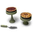 Against a white background, the doll baked goods of our pecan pie sits complete on the tall pie stand and the whole apple pie in the shorter pie stand. The matching pie server lays below in front. Against a white background, the doll baked goods of our pecan pie sits complete on the tall pie stand and the whole apple pie in the shorter pie stand. The matching pie server lays below in front.