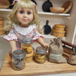 Nellie 18 inch doll standing at counter with 3 mini mason jars filled with 18 inch doll cookies.