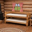 A miniature wooden 18-inch doll trundle bed with plain white mattresses set inside a log cabin beneath a small window with red checkered curtains.